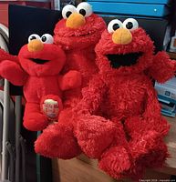 All three Elmo plush dolls grouped together