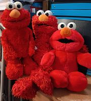 Three Elmo plush toys grouped together