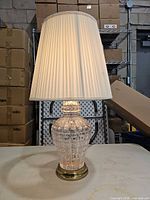 Full view of lamp showing glass body, brass base, pleated shade