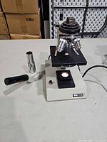 Overall view of microscope showing base, stage, nosepiece, detached eyepiece tube and power cord