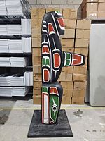Front view of painted wooden totem pole showing full height and color scheme
