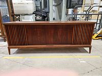 Front view of wood console stereo showing slatted speaker grilles and overall cabinet