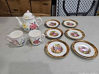 Teapot, two mugs and six plates arranged on table