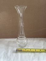 Full view of clear etched glass bud vase with tape measure for width