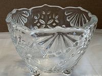 Side view showing exterior pattern, scalloped rim and three feet