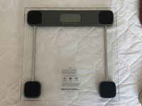 Front view of Beautural digital scale showing glass platform, display, sensor feet