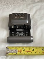 Front view showing Energizer logo, LED, open battery tray marked AA, tape measure for scale