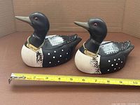 Two ceramic loons coin banks with ruler for scale