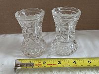 pair of cut glass vases beside ruler showing size