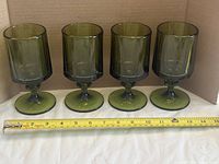 Four green octagonal footed glasses lined up with tape measure