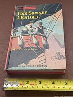 Front cover showing title, author, cover art and measuring tape for scale