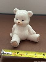 Front and side view of ceramic polar bear cub figurine with tape measure for scale