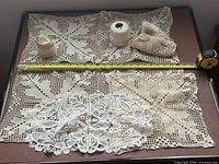 Overview of crocheted squares, thread balls, needle and tape for scale