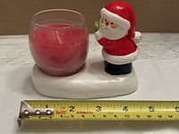 Front view showing Santa figure, glass votive with red candle and measuring tape for length