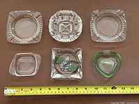 All six ashtrays laid out with tape measure for scale