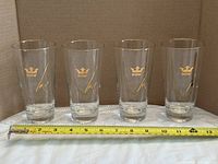 Front view of all four Dow beer glasses with measuring tape showing height