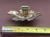 Side view of brass oak leaf candle holder with measuring tape showing width to about 4 inches