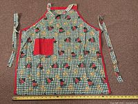 Full apron laid flat with measuring tape showing width and attached neck and waist ties