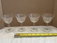 Front view of all four etched cornflower wine glasses with tape measure showing approximate width