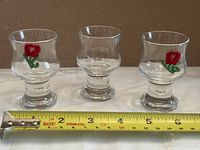 Three footed liqueur glasses beside tape measure