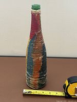 Full view of bottle next to tape measure showing height