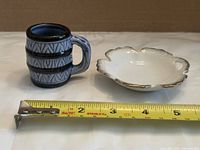 Shooter mug beside gold-rimmed dish with tape measure for scale