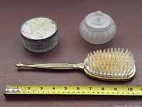 Brush and two jars with measuring tape for scale