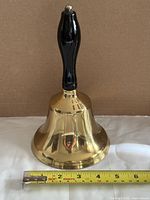 Full view of brass bell with tape measure for scale