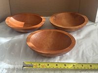 Three hardwood bowls with tape showing diameter