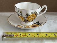 Cup nestled in saucer beside measuring tape showing approximate diameter