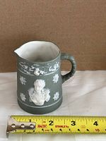 Front view showing relief bust, spout, tape for length