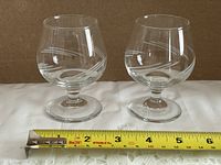Front view of both glasses side by side with tape measure for scale