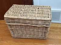 Closed rectangular wicker hamper on hardwood floor