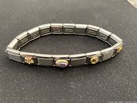 Full bracelet view showing stainless steel links and several decorated charms