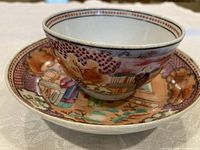 Tea bowl resting on saucer showing exterior and interior decoration