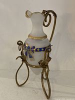 Satin glass vase in metal stand, frontal view showing gilt ribbon motif