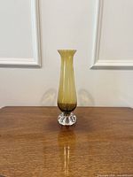 Full front view of amber-yellow vase on wood surface