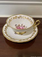Teacup nested on saucer showing rose motif and gold trim