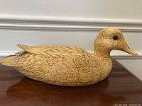 Left side profile of carved wooden duck decoy on wooden surface