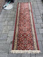 Full view of the red floral wool runner rug laid flat showing overall design and fringed ends