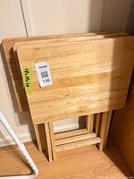 Three folded wooden tray tables leaning against wall