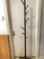 Full view of wooden coat rack leaning against door