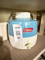 Front view of blue and white Coleman beverage cooler with spigot and handle