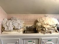 Folded stacks of assorted light-colored curtains on counter