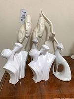 Group shot showing all seven white ceramic figurines on tabletop