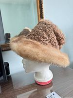 Side view of hat on mannequin head showing shearling crown and fur brim
