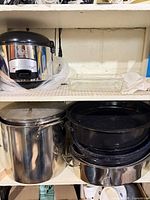 Shelf with rice cooker, glass dish, stock pot, nested black roasters