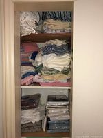 View of three shelves filled with folded linens and towels including packaged sets
