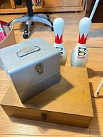 Overall lot showing metal box, wooden box, two bowling pins
