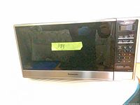 Front view of Panasonic microwave showing stainless steel trim, black glass door, keypad